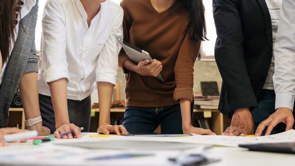 Nahaufnahme: Menschen im Workshop stützen sich auf Tisch